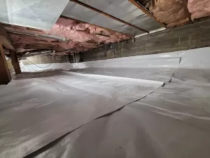 Under house crawl space with white plastic membrane on all of the ground.