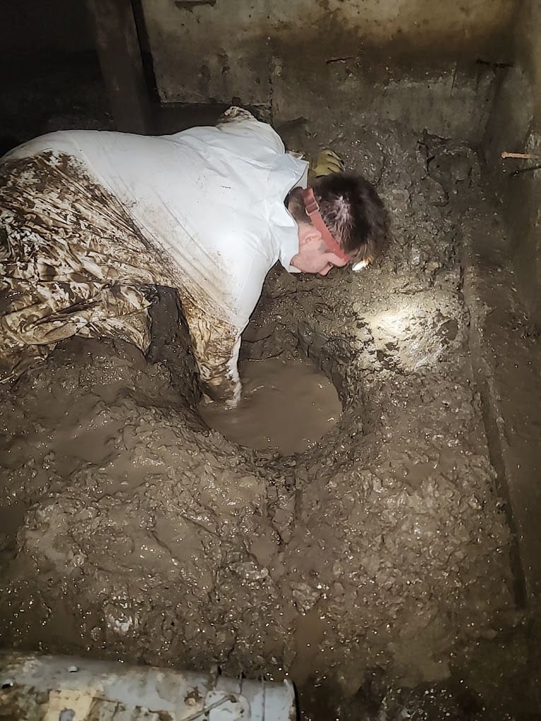 Man working in muddy crawlspace