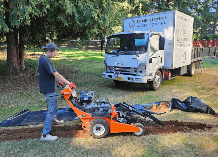 Crew working on digging a trench outdoors with Better Basement truck in the distances.