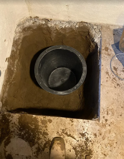 Sump pump in dirt trench in a basement
